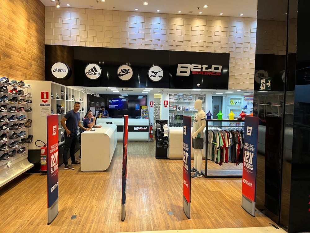 Quatro pedestais antifurto com painéis publicitários na entrada de uma loja de artigos esportivos